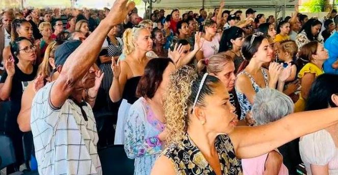 Grupo de jóvenes cubanos reunidos al aire libre con las manos alzadas en oración, símbolo de fe y esperanza en medio de la crisis económica.